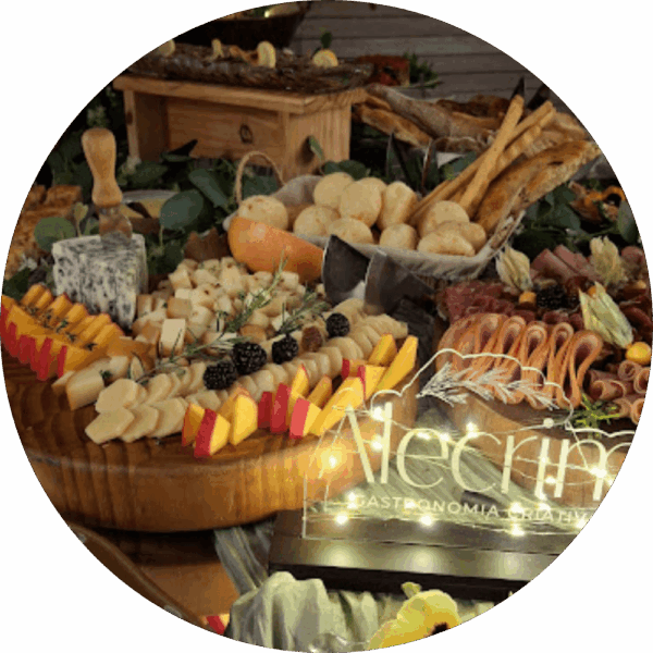 Mesa gastronômica da Alecrim para eventos, decorada com tábuas de queijos finos, charcutaria, pães de queijo e frutas. Em destaque, um letreiro luminoso com o nome da marca entre as iguarias, criando uma experiência visual e sensorial de luxo para celebrações em Belo Horizonte.