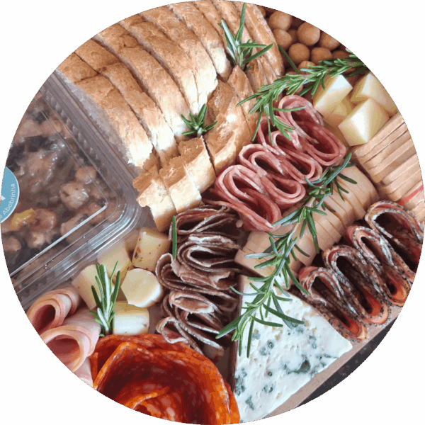 Tábua de frios gourmet da Alecrim com pães artesanais fatiados, queijo gorgonzola, queijos finos em cubos e charcutaria selecionada. A composição artística inclui ramos de alecrim fresco e antepasto de abobrinha, ideal para experiências gastronômicas de luxo e eventos em Belo Horizonte.