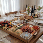 Mesa posta sofisticada com a Platter GG da Alecrim Gastronomia, a maior da linha, com aproximadamente 3,8kg. A tábua farta atende de 10 a 14 pessoas e apresenta uma curadoria completa de queijos, charcutaria, pães e frutas frescas, ideal para grandes recepções e eventos de luxo em Belo Horizonte.