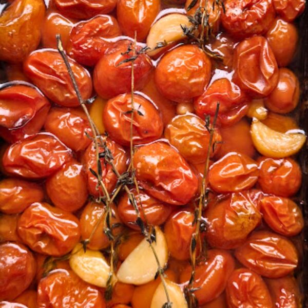 Antepasto artesanal de tomatinhos confitados da Alecrim, cozidos lentamente em azeite de oliva com dentes de alho e ramos de tomilho. A imagem em close-up destaca a suculência e o brilho dos tomates, ideal para acompanhar pães artesanais e compor mesas gastronômicas sofisticadas em Belo Horizonte.