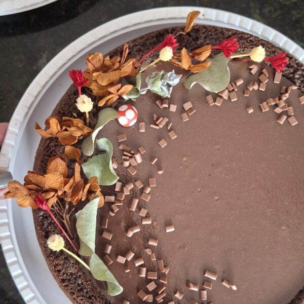 Bolo festivo chocolatudo da Alecrim visto de cima, com massa de cacau e cobertura brilhante de brigadeiro. O bolo de 1,8kg é decorado com um arranjo artístico de flores secas e granulados gourmet, representando uma opção de sobremesa sofisticada e artesanal para aniversários e celebrações em Belo Horizonte.