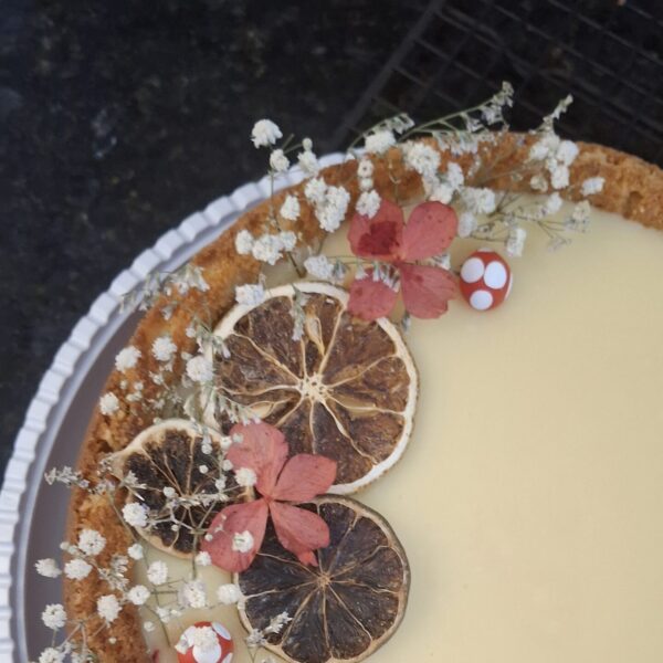 Bolo festivo de laranja da Alecrim com cobertura cremosa de brigadeiro de capim-santo verde e raspas de laranja. O bolo artesanal de 1,8kg é apresentado em um prato de servir, unindo o sabor cítrico com o toque herbáceo, ideal para festas, cafés da manhã especiais e brunchs em Belo Horizonte.