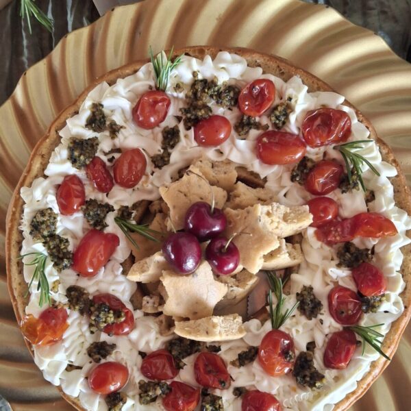 Guirlanda Caprese artesanal da Alecrim Gastronomia, apresentada em bandeja dourada com base de cream cheese, cobertura de tomates confitados, pesto e ramos de alecrim. No centro, estrelas de pão e cerejas decoram a iguaria, ideal para mesas de antepastos e eventos sofisticados em Belo Horizonte.