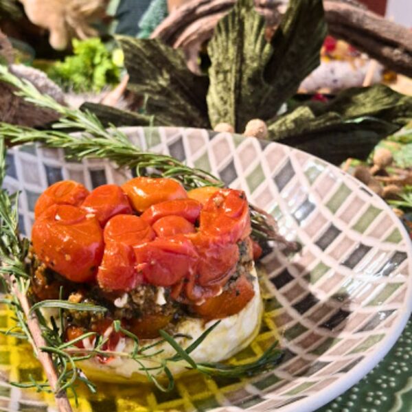 Torre de antepasto artesanal da Alecrim composta por camadas de cream cheese, pesto de ervas e cobertura de tomates confitados. A iguaria é servida em bowl de cerâmica decorada e finalizada com ramos de alecrim, representando a gastronomia criativa para eventos e recepções em Belo Horizonte.