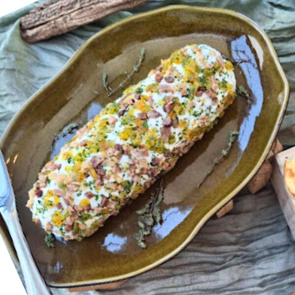 Terrine de queijo artesanal da Alecrim com crosta colorida de damasco, bacon e ervas, servida em travessa cerâmica verde. O antepasto gourmet integra o catálogo de iguarias para eventos intimistas e presentes sofisticados em Belo Horizonte, unindo estética e sabor afetivo.