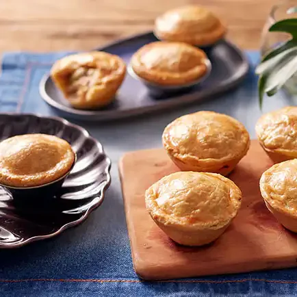 Bandeja com seis unidades de Empadas da Vila da Alecrim, feitas com massa podre amanteigada e recheio suculento de frango. As empadas douradas estão dispostas em uma tábua de madeira, representando uma opção clássica e sofisticada de lanche ou buffet para eventos em Belo Horizonte.