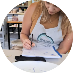 Mulher participando de workshop de pintura em cerâmica da Alecrim, focada no processo criativo manual. A atividade une gastronomia e arte, oferecendo uma vivência de pausa e conexão para quem busca momentos de autocuidado e aprendizado artesanal em Belo Horizonte.