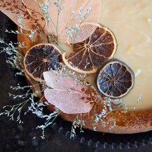 Bolo festivo artesanal de laranja com cobertura de brigadeiro de capim-santo e decoração com frutas desidratadas
