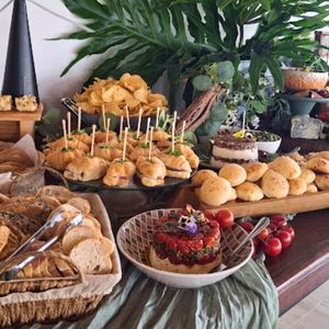 Mesa com iguarias artesanais da Alecrim incluindo sanduíche caprese, pão de queijo mineiro e torre caprese - Portfólio Alecrim Gastronomia