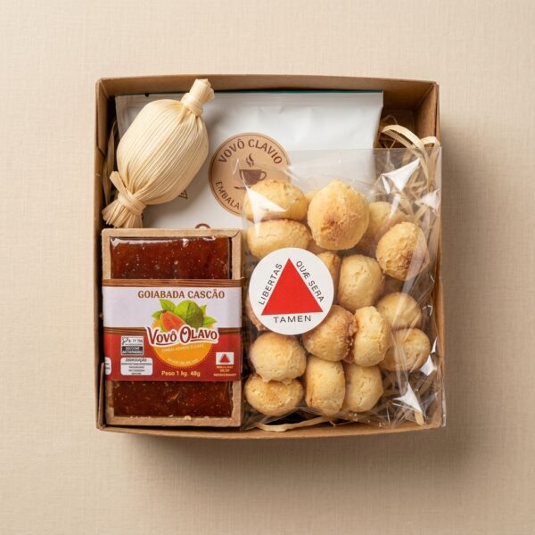 Caixa retangular em papel kraft, posicionada verticalmente sobre fundo neutro, contendo um kit gourmet com goiabada, doce de leite, biscoitos e café, organizados de forma centralizada com iluminação suave de estúdio.
