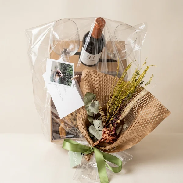 Experiência gourmet 'Quer Vin? Vem!' da Alecrim Gastronomia Criativa. Caixa de madeira artesanal com vinho importado, duas taças de vidro e tábua de charcutaria completa com queijos, salames, pães, antepastos e frutas frescas como morangos e physalis, decorada com alecrim.