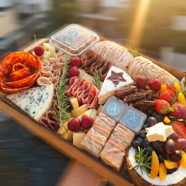 Tábua de frios de luxo, composta por charcutaria selecionada, queijos finos, torradas, pesto, castanha, morango e uvas.