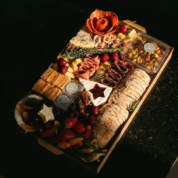 Tábua de frios de luxo, composta por charcutaria selecionada, queijos finos, torradas, pesto, castanha, morango e uvas.
