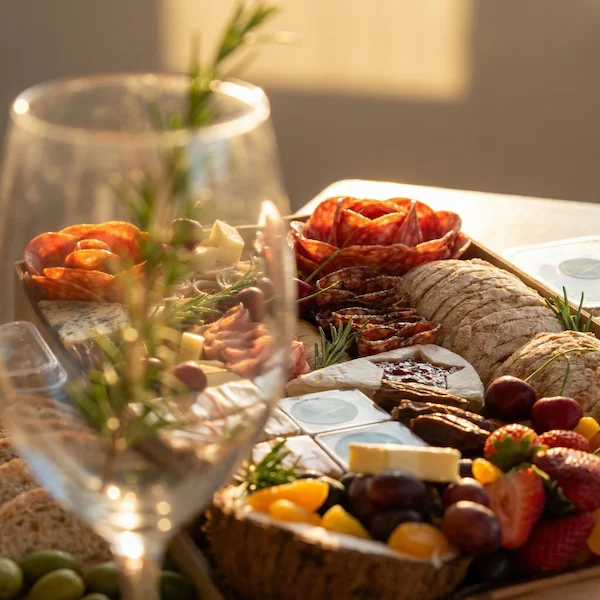 Tábua de frios de luxo, composta por charcutaria selecionada, queijos finos, torradas, pesto, castanha, morango e uvas.