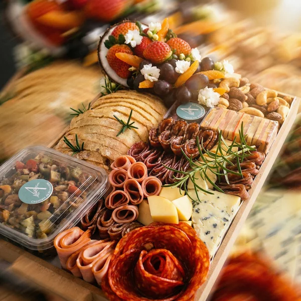 Tábua de frios de luxo, composta por charcutaria selecionada, queijos finos, torradas, pesto, castanha, morango e uvas.