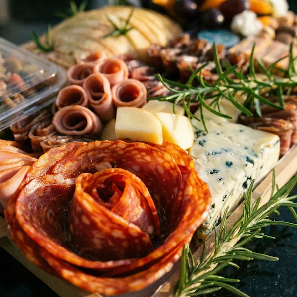 Tábua de frios de luxo, composta por charcutaria selecionada, queijos finos, torradas, pesto, castanha, morango e uvas.