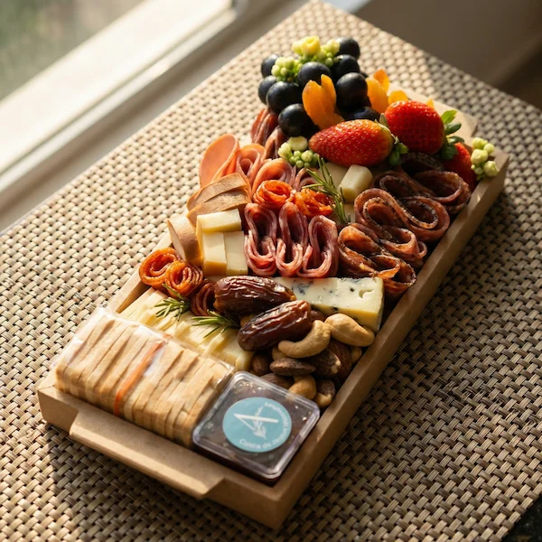 Tábua de frios de luxo, composta por charcutaria selecionada, queijos finos, torradas, pesto, castanha, morango e uvas.