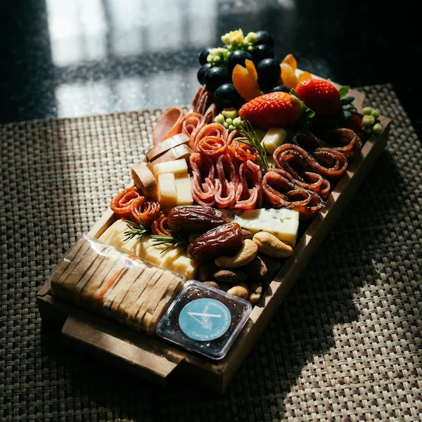 Tábua de frios de luxo, composta por charcutaria selecionada, queijos finos, torradas, pesto, castanha, morango e uvas.
