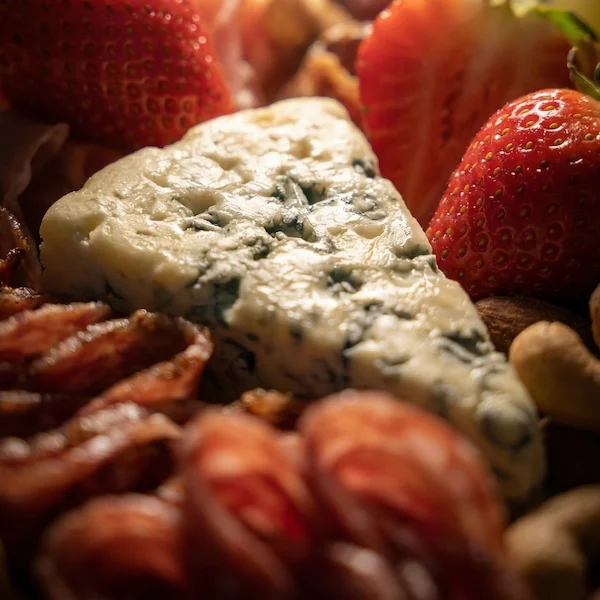 Tábua de frios de luxo, composta por charcutaria selecionada, queijos finos, torradas, pesto, castanha, morango e uvas. 