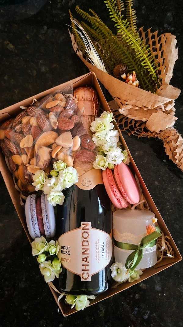 Caixa de presente kraft Box Meu Momento vista de cima, contendo mini espumante Chandon Rosé, macarons, mix de nuts e vela artesanal da Alecrim BH.