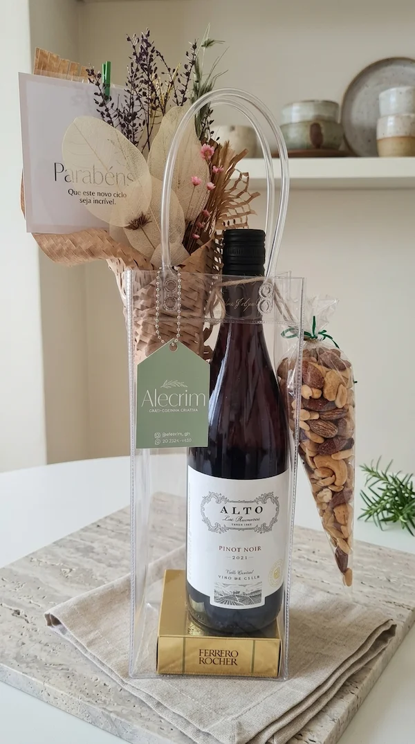 Wine Bag transparente da Alecrim Gastronomia em BH contendo vinho Pinot Noir, chocolates Ferrero Rocher, mix de nuts e buquê de flores secas.