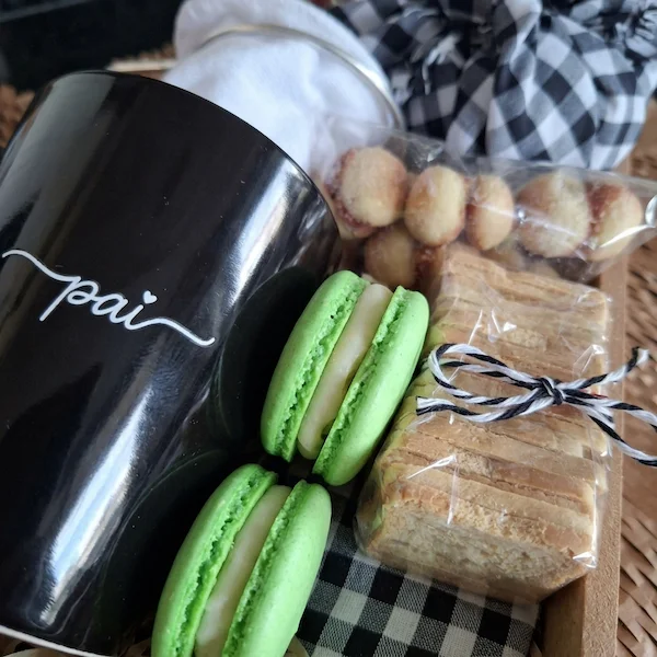 Cesta de café da manhã individual para o Dia dos Pais em BH da Alecrim Gastronomia Criativa, montada em caixa de madeira reutilizável com caneca preta personalizada 'Pai', coador de pano, macarons verdes, biscoitos artesanais e geleia caseira, decorada com trigo seco e tecido xadrez.